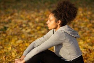 A young African American woman in athletic wear rests outdoors.