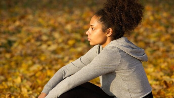 A young African American woman in athletic wear rests outdoors.