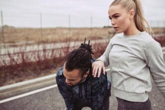A young couple pauses, catching their breath after a run, suggesting exertion and shared activity.