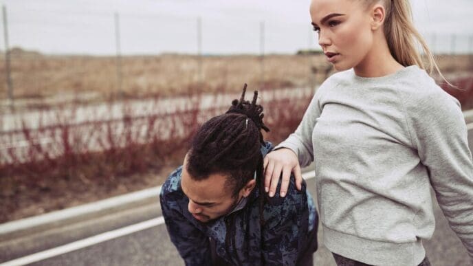 A young couple pauses, catching their breath after a run, suggesting exertion and shared activity.