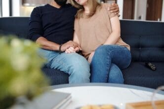 Young couple on a sofa embraces, holding hands and showing affection.