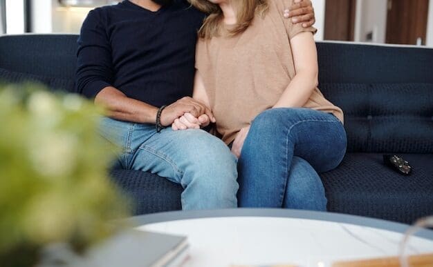 Young couple on a sofa embraces, holding hands and showing affection.