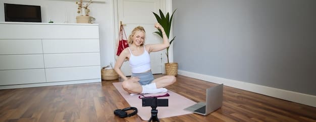 Young woman, a fitness instructor, sits on a rubber mat, recording a video on a digital device.
