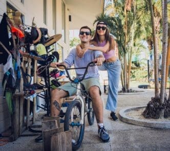A young couple smiles while riding BMX bikes at a skatepark.