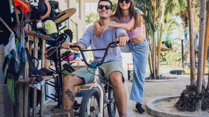 A young couple smiles while riding BMX bikes at a skatepark.