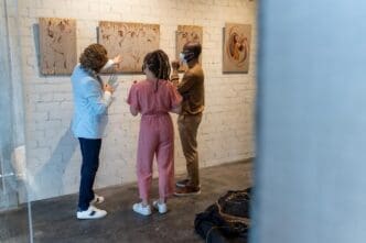 A young couple wearing masks listens to a mature artist.