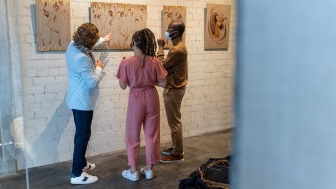 A young couple wearing masks listens to a mature artist.