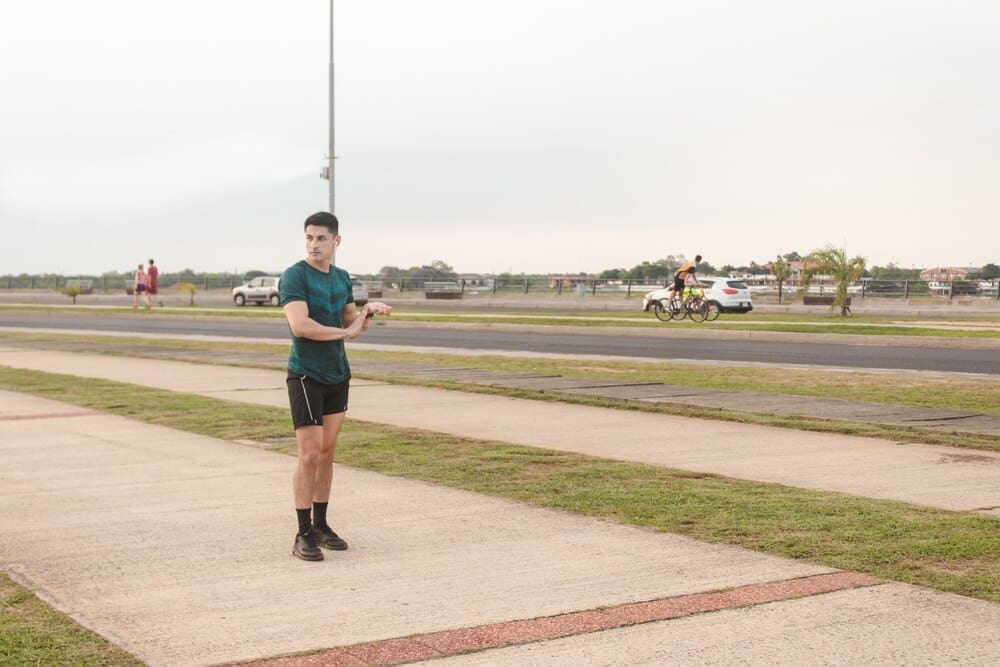 A young man stretches before starting a jog on a waterfront path.