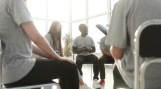 A diverse group of young people are gathered around a table, engaged in discussion.