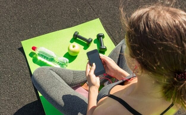 A young woman in athletic wear uses a smartphone while standing on a stadium track.