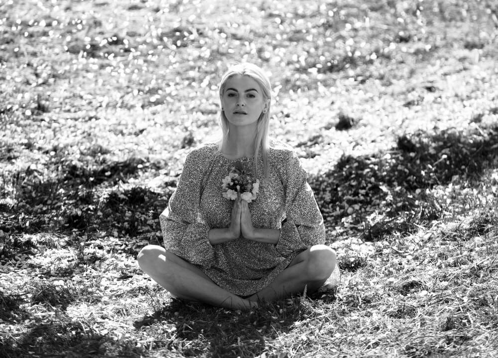 Young woman reclines among blooming pink cherry blossom flowers.