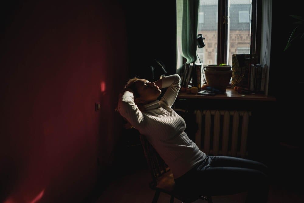 A young woman sits in a chair indoors.