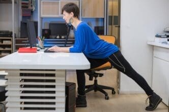 A young woman stretches her arms overhead in an office setting.