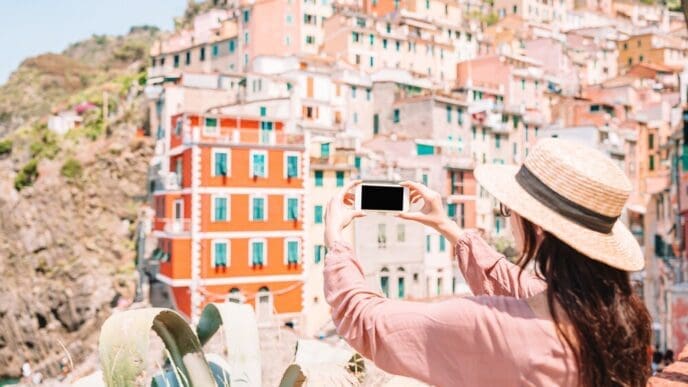 A young woman enjoys a scenic view of Riomaggiore, a colorful village in Cinque Terre, Italy.