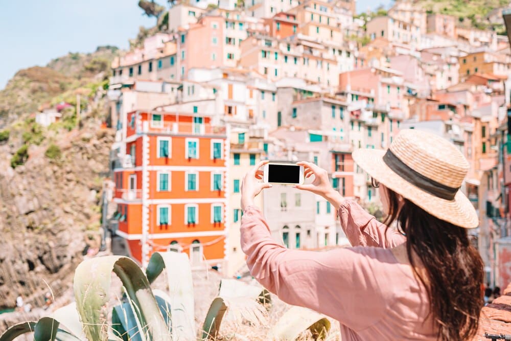 A young woman enjoys a scenic view of Riomaggiore, a colorful village in Cinque Terre, Italy.