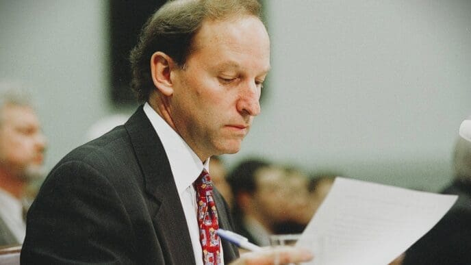 A man in a suit and tie, Abbe D. Lowell, looks down at a document he is holding