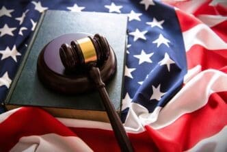 A judge's gavel rests on a law book on top of a wrinkled American flag