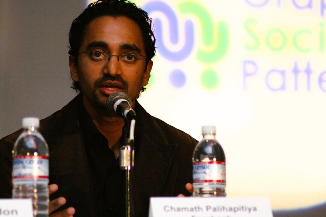 A close-up portrait of billionaire Chamath Palihapitiya speaking into a microphone at a conference in San Jose.