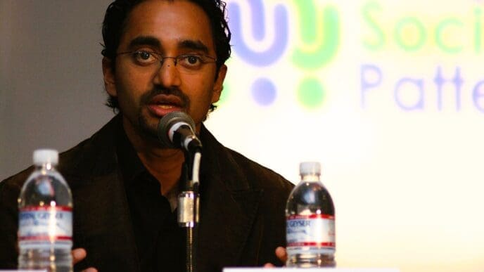 A close-up portrait of billionaire Chamath Palihapitiya speaking into a microphone at a conference in San Jose.