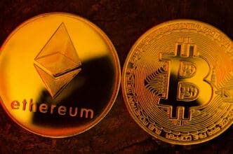 A close-up, macro photograph of a shiny golden Ethereum coin positioned side-by-side with a golden Bitcoin coin.