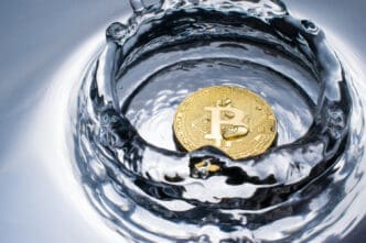 A close-up, high-speed photograph of a golden Bitcoin coin at the bottom of a pool of water, with ripples and splashes around it.