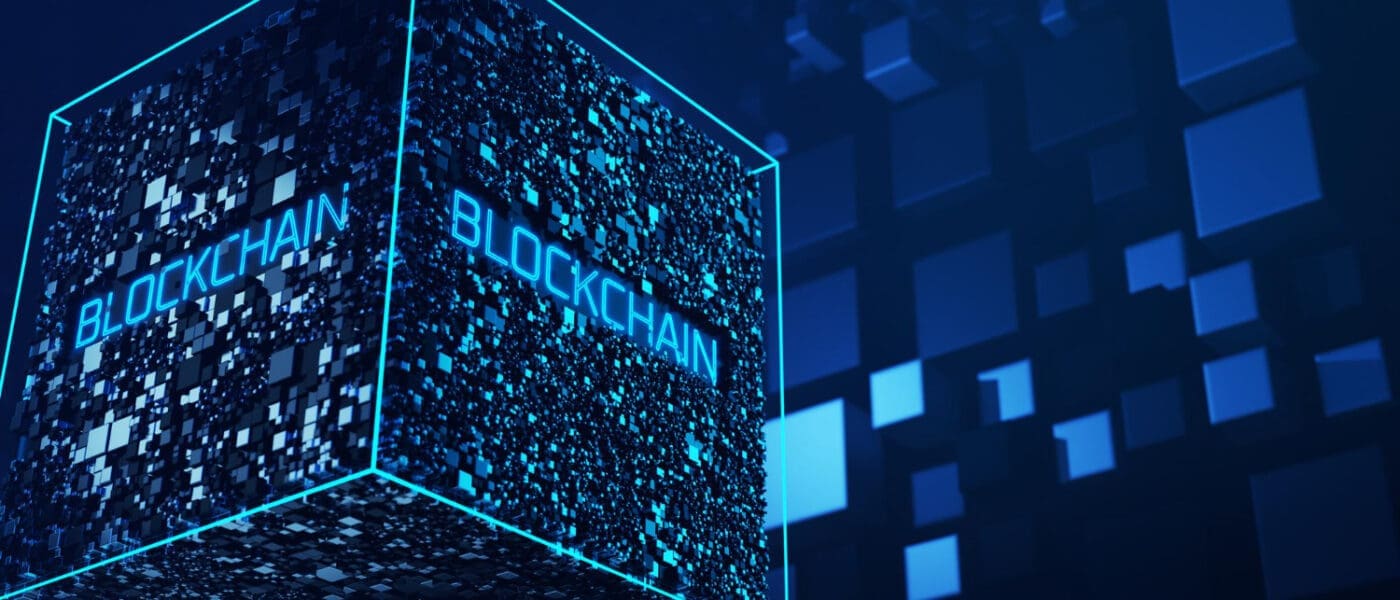A conceptual 3D render of a large, glowing blue cube made up of smaller blocks, with the word "BLOCKCHAIN" written on its sides.
