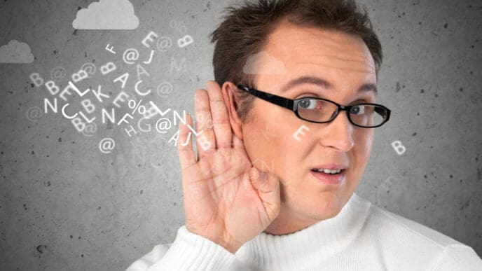 A man with glasses and a white sweater holds his hand to his ear, as if listening intently, with a cloud of floating letters and symbols around his head, against a grey background with hand-drawn clouds.
