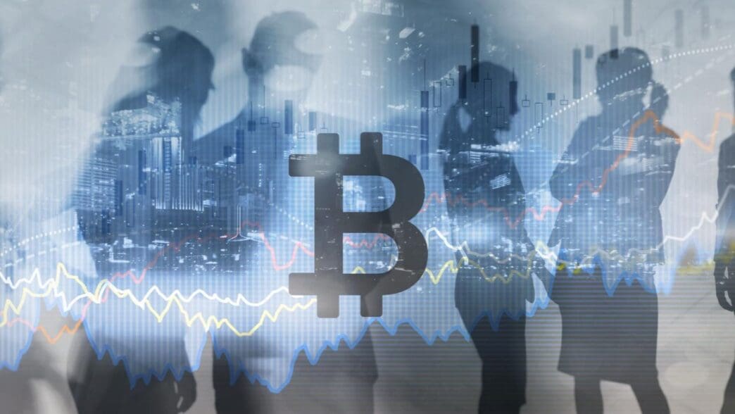 A conceptual image with the large silhouette of a Bitcoin symbol in the center, overlaid on blurry figures of businesspeople, a city skyline, and financial line graphs.