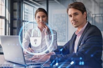 A man and a woman are seated at a table with a laptop, with a glowing digital overlay of a padlock icon and a circular network, symbolizing a discussion about cyber security or data protection.