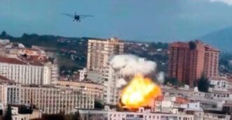 A plane flies over a city where an explosion is erupting from a building