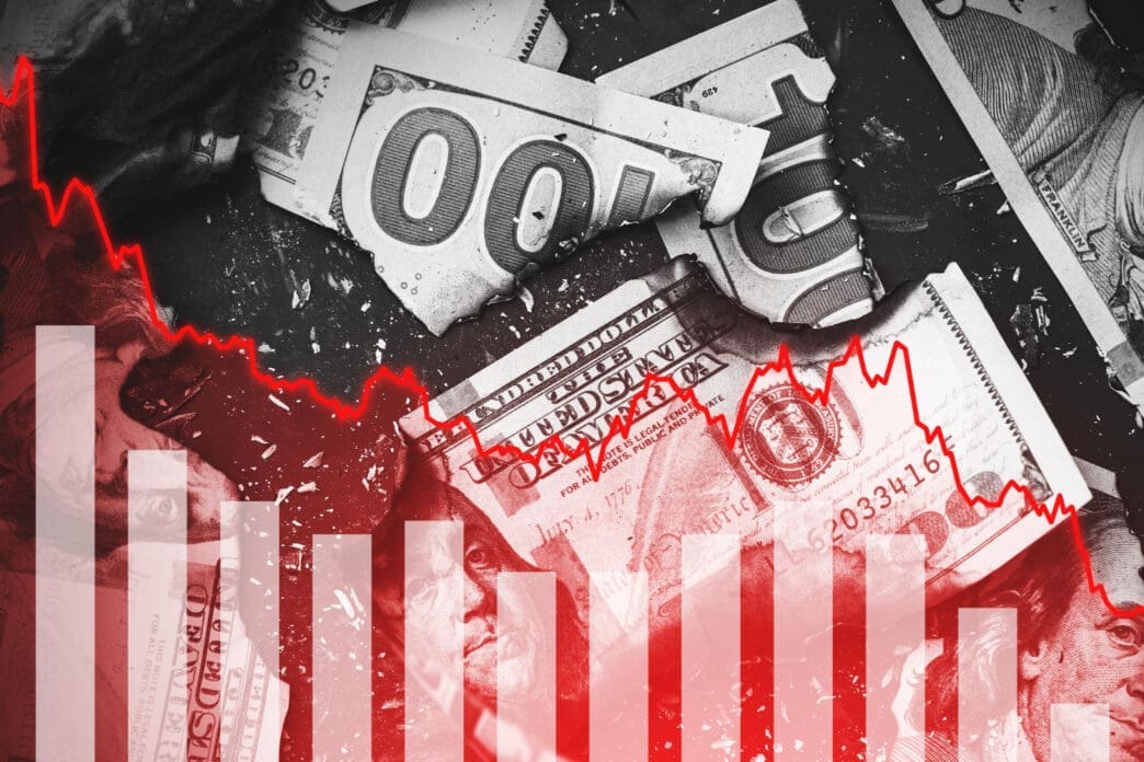 A financial chart with a red, downward-trending line and bar graph is overlaid on a background of crumpled and burned hundred-dollar bills.