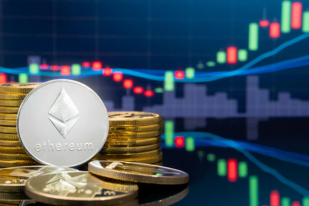 A silver Ethereum coin stands in the foreground, surrounded by gold coins, with a rising digital financial chart in the blurry background.