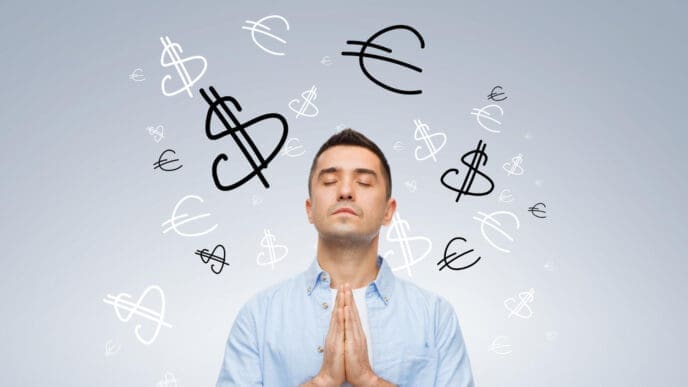 A man with his eyes closed and hands clasped in front of him, surrounded by floating dollar and euro signs.