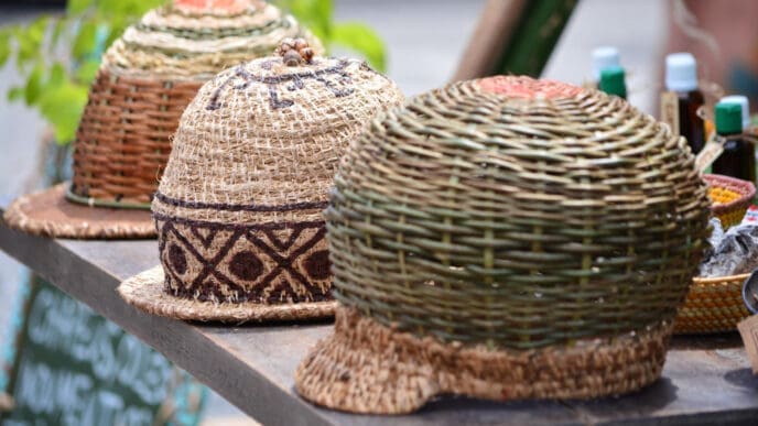 Three hand-woven, beehive-shaped hats are displayed on a wooden table