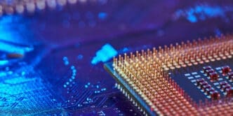 A close-up, macro shot of an Intel processor chip, showing the dense array of golden pins on its underside.