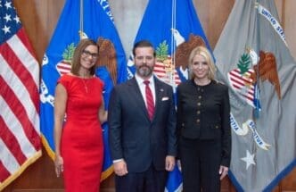 Jason A. Reding Quiñones is sworn in as the U.S. Attorney for the Southern District of Florida, standing with two women in front of three flags.