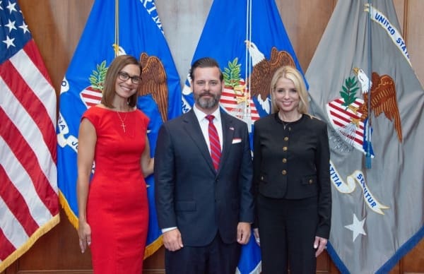 Jason A. Reding Quiñones is sworn in as the U.S. Attorney for the Southern District of Florida, standing with two women in front of three flags.