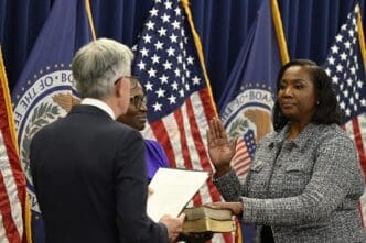 Lisa Cook is sworn in as a member of the Federal Reserve Board of Governors by Chairman Jerome Powell, with her right hand raised over a Bible.