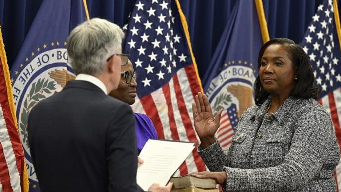 Lisa Cook is sworn in as a member of the Federal Reserve Board of Governors by Chairman Jerome Powell, with her right hand raised over a Bible.