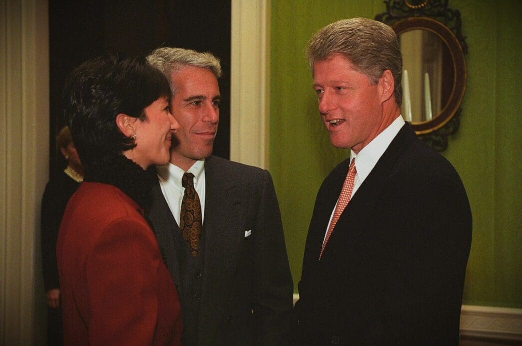 A professional photograph of Bill Clinton, Jeffrey Epstein, and Ghislaine Maxwell standing together and talking at a formal event.