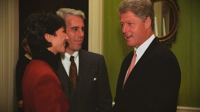 A professional photograph of Bill Clinton, Jeffrey Epstein, and Ghislaine Maxwell standing together and talking at a formal event.