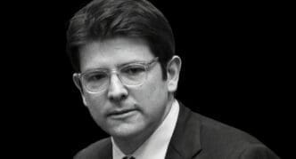 A black and white portrait of Miguel Uribe Turbay, a politician with glasses, wearing a suit and looking to the side with a serious expression.