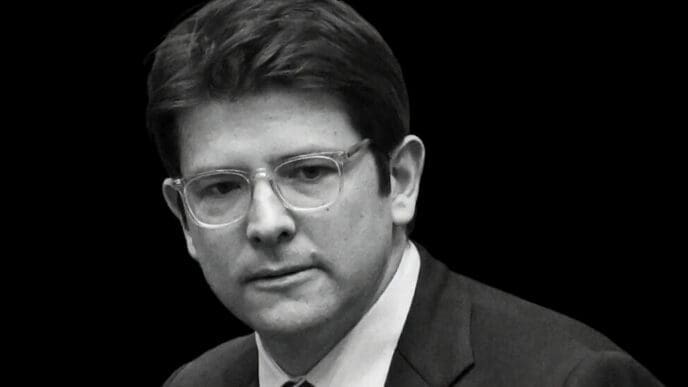 A black and white portrait of Miguel Uribe Turbay, a politician with glasses, wearing a suit and looking to the side with a serious expression.
