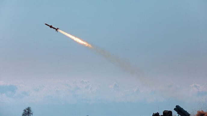 A ground-launched missile soars into the sky from a military vehicle, leaving a fiery trail