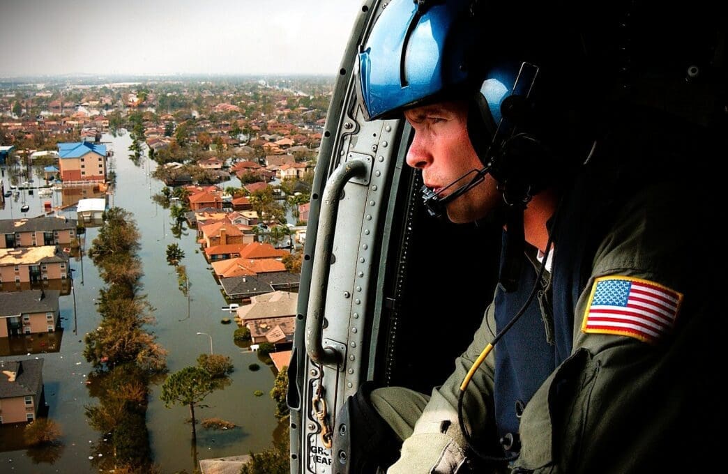 A U.S. Coast Guardsman looks down from a helicopter at a flooded neighborhood in New Orleans