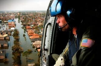 A U.S. Coast Guardsman looks down from a helicopter at a flooded neighborhood in New Orleans