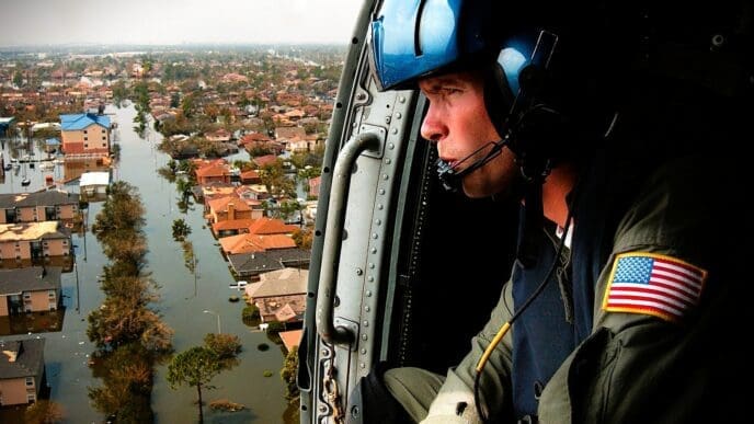 A U.S. Coast Guardsman looks down from a helicopter at a flooded neighborhood in New Orleans