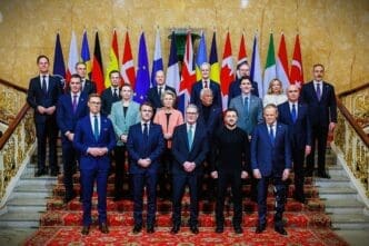 A group of world leaders, including President Volodymyr Zelenskyy, are posed for a group photo on a grand staircase with many international flags behind them.