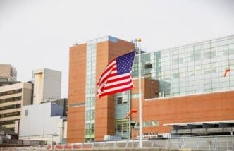 The American flag waves in front of a modern hospital or public health building
