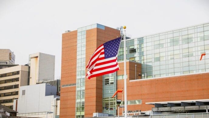 The American flag waves in front of a modern hospital or public health building